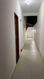 an empty hallway with white walls and a wooden door at CASA K in Barra de São Miguel