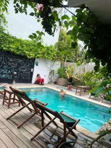- une piscine avec des chaises et des personnes y jouant dans l'établissement Tipsea Turtle Rooftop Hostel Gili Trawangan, à Gili Trawangan