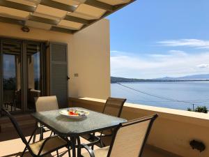 a table and chairs on a balcony with a view of the water at Cozy Sunset House in Aegina Town