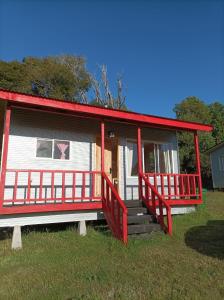 a red and white house with a red porch at cabañas aulen chepu chiloe in Ancud