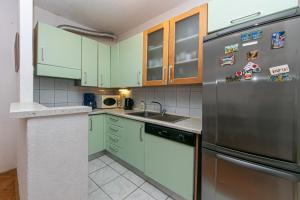 eine Küche mit grünen Schränken und einem Kühlschrank aus Edelstahl in der Unterkunft Apartments by the sea Tucepi, Makarska - 19857 in Tučepi