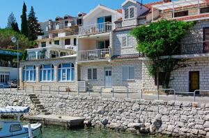 um grupo de casas ao lado de uma parede de pedra e água em Apartments by the sea Brna, Korcula - 20827 em Smokvica
