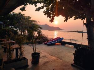 a boat on the beach with the sunset in the background at Sea Sand House Resort in Klong Wan