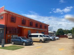 a group of cars parked in a parking lot in front of a building at Tomato Backpackers in Bundaberg