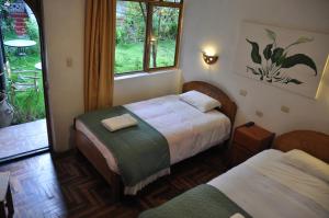 a bedroom with two beds and a window at Las Orquideas Ollantaytambo in Ollantaytambo