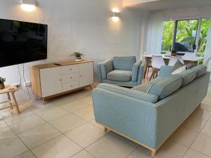 uma sala de estar com um sofá e cadeiras e uma televisão em Reef Resort Villas Port Douglas em Port Douglas