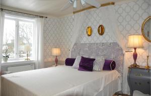 a bedroom with a white bed with purple pillows at Gorgeous Home In Finnestad With Wifi in Säffle