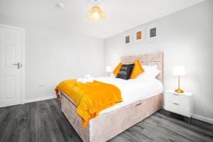 een witte slaapkamer met een groot bed met een oranje deken bij Modern home in Birmingham