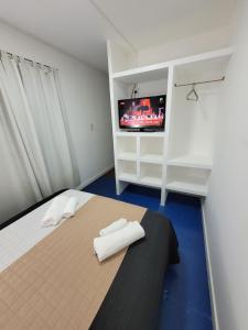 1 dormitorio con 1 cama y TV en la pared en Departamento Desire en Puerto Deseado