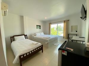 a hotel room with two beds and a desk and a desk at Baan Ruay Suk Resort, Lopburi in Lop Buri