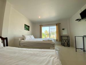 a hotel room with two beds and a window at Baan Ruay Suk Resort, Lopburi in Lop Buri