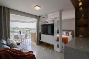 1 dormitorio con 1 cama, TV y balcón en Sunrise Studio - GRU 413, en Guarulhos