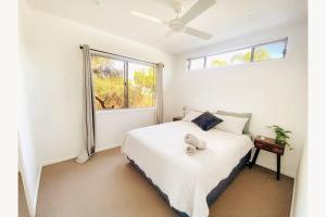 ein Schlafzimmer mit einem weißen Bett und einem Fenster in der Unterkunft Beach House with spa among the trees Coolum Beach in Coolum Beach