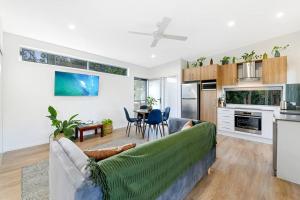 a living room with a couch and a kitchen at Beach House with spa among the trees Coolum Beach in Coolum Beach