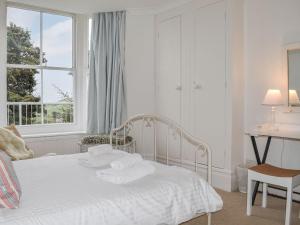um quarto com uma cama branca e toalhas em Caerleon em Salcombe