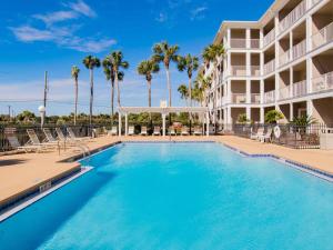a swimming pool in front of a building with palm trees at Grand Caribbean Perdido Key #101 West in Perdido Key