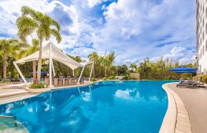 聖羅莎的住宿－Seda Nuvali，拥有蓝水和棕榈树的度假村的游泳池