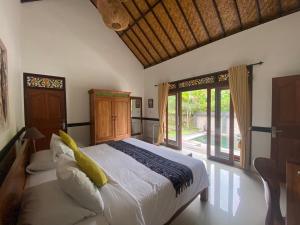 a bedroom with a large bed and a large window at Agung Village in Tanah Lot