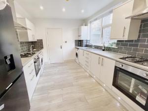 una cucina con armadietti bianchi e pavimenti in legno di Modern Room in Centrally Located Apartment - Room 4 a Londra