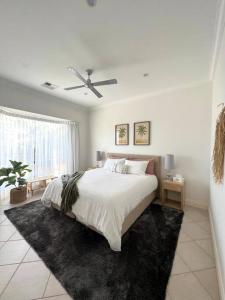 a white bedroom with a bed and a ceiling fan at Zentala in Port Lincoln
