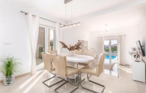 a white dining room with a white table and chairs at Awesome Home In Martinscica With 3 Bedrooms, Wifi And Outdoor Swimming Pool in Martinšćica