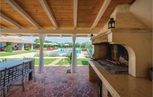 a patio with an outdoor fireplace with a pool in the background at Gorgeous Home In Tar With Wifi in Tar
