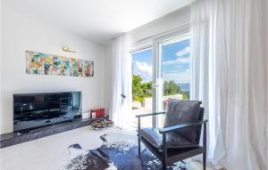 a living room with a fireplace and a chair and a television at Beautiful Home In Naklice With Kitchen in Gata