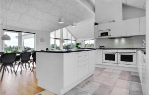 cocina con armarios blancos, mesa y sillas en Stunning Home In Stege With Sauna, en Stege
