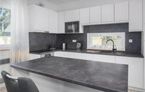 eine Küche mit weißen Schränken und einer schwarzen Arbeitsplatte in der Unterkunft Cozy Home In Porec With Kitchen in Poreč