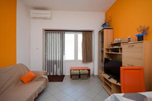 um quarto com um sofá e uma televisão num quarto em Apartments Mirjana em Lopar