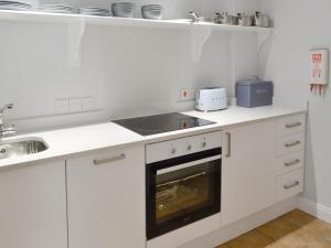 a white kitchen with a stove and a sink at Sweet Briar - 8234 in Bridport