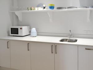 a white kitchen with a microwave and a sink at Sweet Briar - 8234 in Bridport