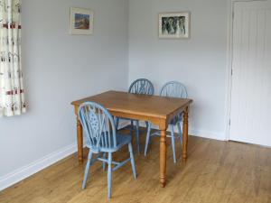 een houten tafel met vier stoelen eromheen bij Buzzards - 8235 in Bridport