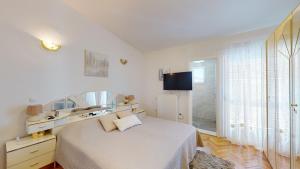 a white bedroom with a bed and a mirror at Villa Almas in Neorić