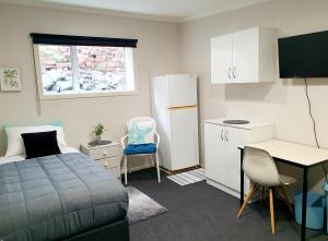 a bedroom with a bed and a desk and a table at Travel Stay Centre City Hostel in Dunedin