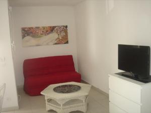 sala de estar con sofá rojo y TV en Appartement Balaruc-les-Bains, 2 pièces, 4 personnes - FR-1-680-13 en Balaruc-les-Bains