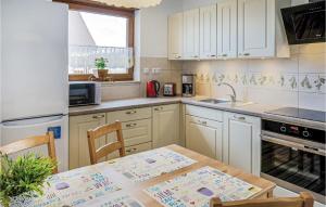a kitchen with white cabinets and a table and a sink at 3 Bedroom Awesome Home In Mscicie in Podamirowo