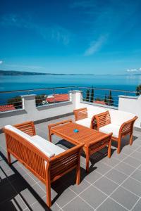 a patio with four chairs and a wooden table at Nemira Sunny Apartments in Omiš