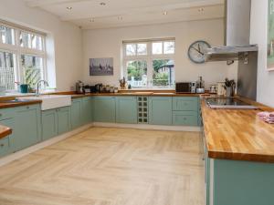 a kitchen with green cabinets and a wooden floor at Penarvon House in Helford