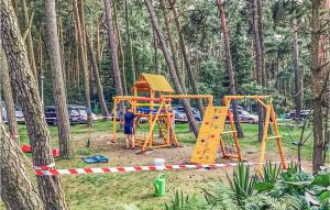 a man standing next to a playground in a park at 3 Bedroom Lovely Apartment In Lukecin in Łukęcin