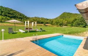 una piscina con sillas y un patio con sombrilla en Beautiful Home In Piobbico With House A Panoramic View, en Piobbico