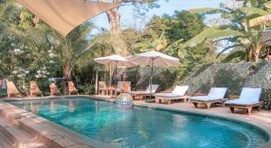 - une piscine avec des chaises, des tables et des parasols dans l'établissement Hotel Michanti, à El Zonte