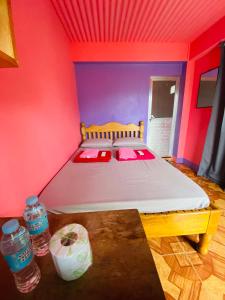 Cama en habitación con paredes rojas y moradas en Batad Hillside Inn and Restaurant, en Banaue