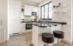 a kitchen with white cabinets and black counter stools at Amber in Binz