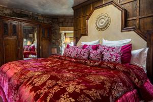 1 dormitorio con 1 cama grande con mantas y almohadas rojas en Craigiehall Temple, en Edimburgo