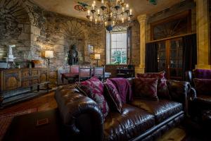 a living room with a brown leather couch and a chandelier at Craigiehall Temple in Edinburgh
