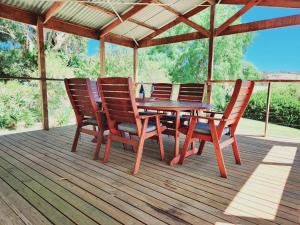 a wooden table and chairs on a wooden deck at Yaringa Cottage, ultimate entertainer! in Encounter Bay