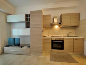 cocina con armarios de madera, fregadero y TV en Roma 202 by Tempovacanza, en Laigueglia