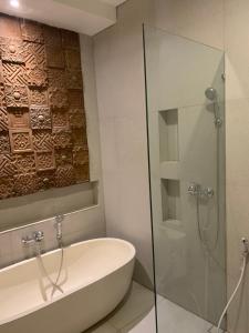 La salle de bains est pourvue d'une baignoire et d'une douche en verre. dans l'établissement The Hita Apartement, à Seminyak