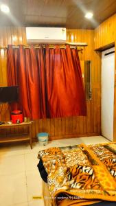 1 dormitorio con cama y cortina roja en altafs motel en Matheran